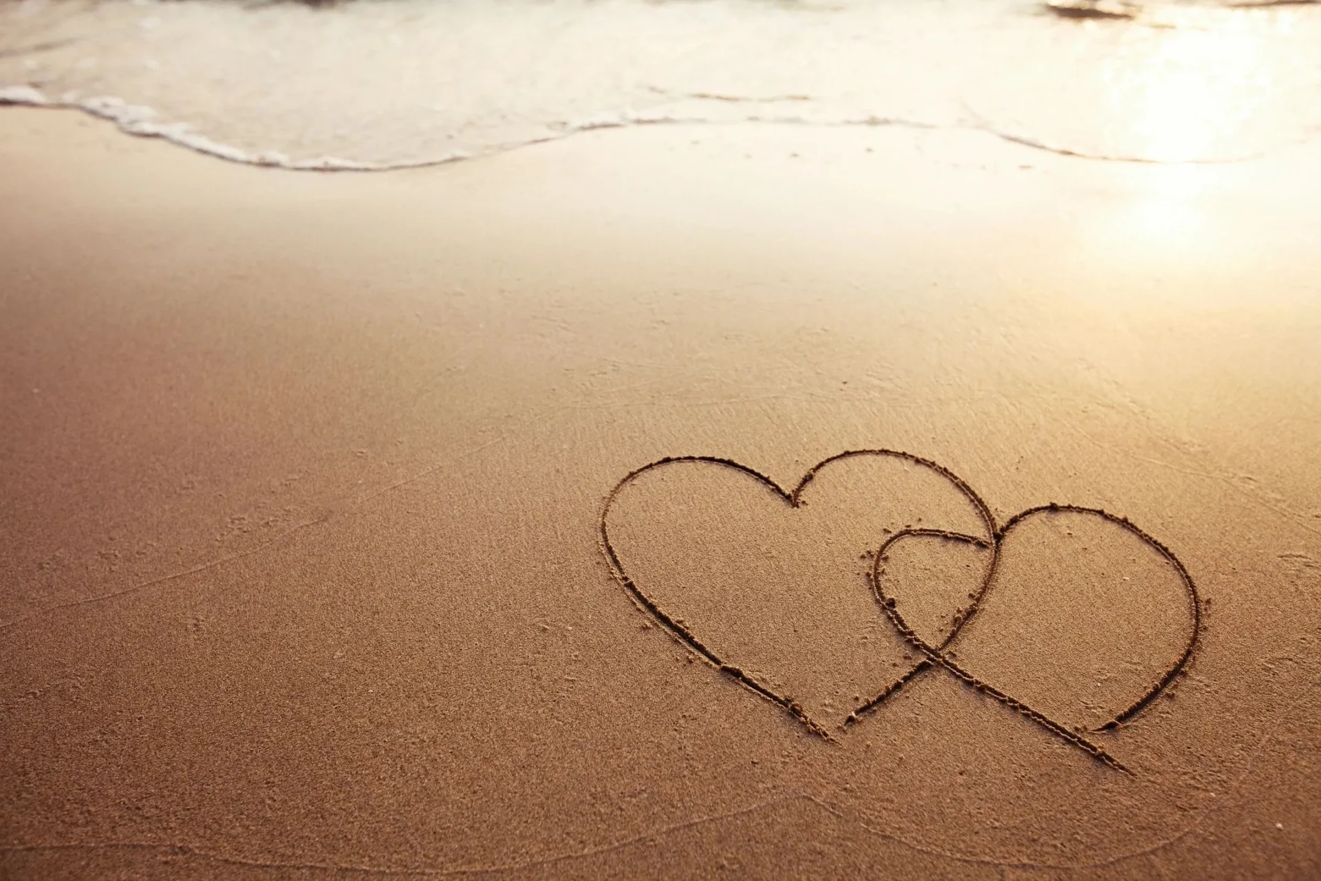 Two hearts drawn in the sand on a beach.