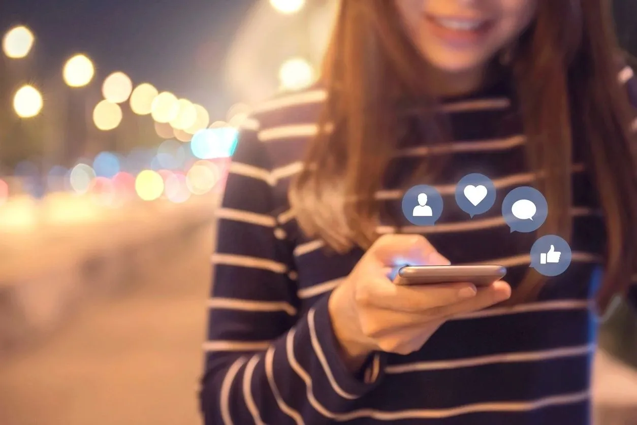 A woman holding her phone in front of a street.