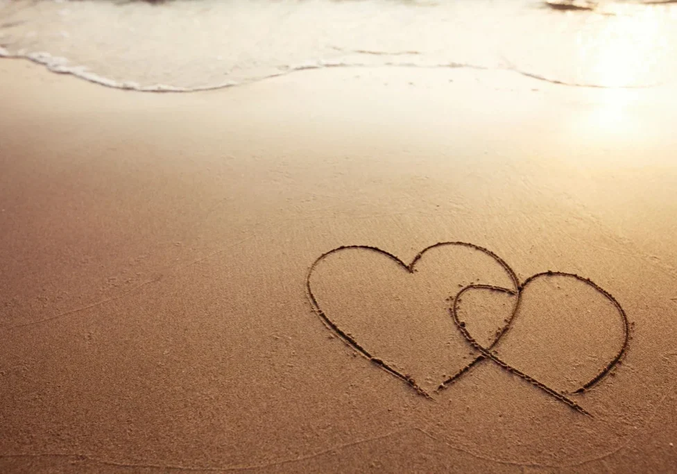 Two hearts drawn in the sand on a beach.